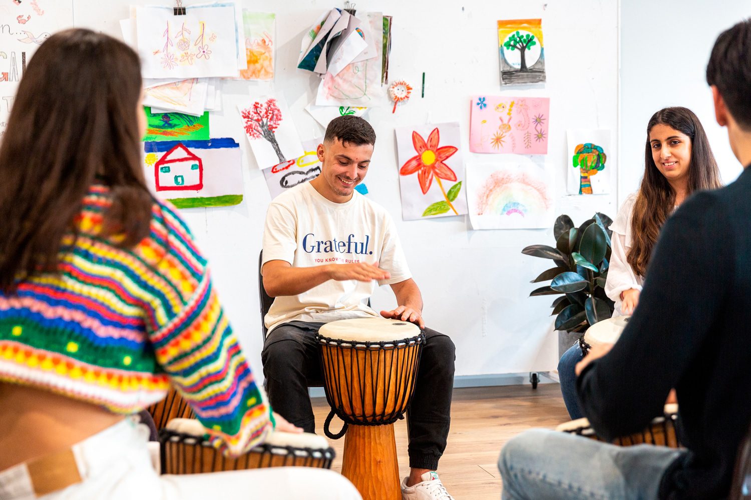 A group playing hand drums together in a bright room