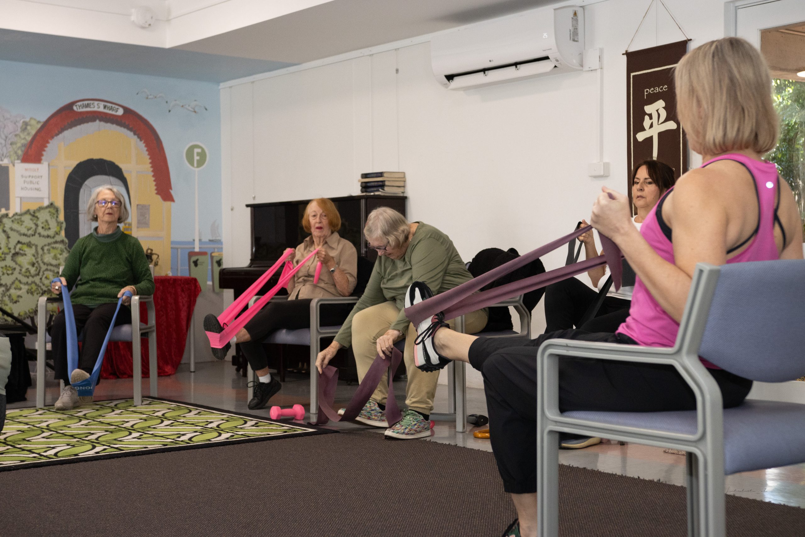 A seated exercise class working with resistance bands in the community room
