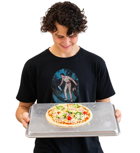 A young man holding a tray with a pizza