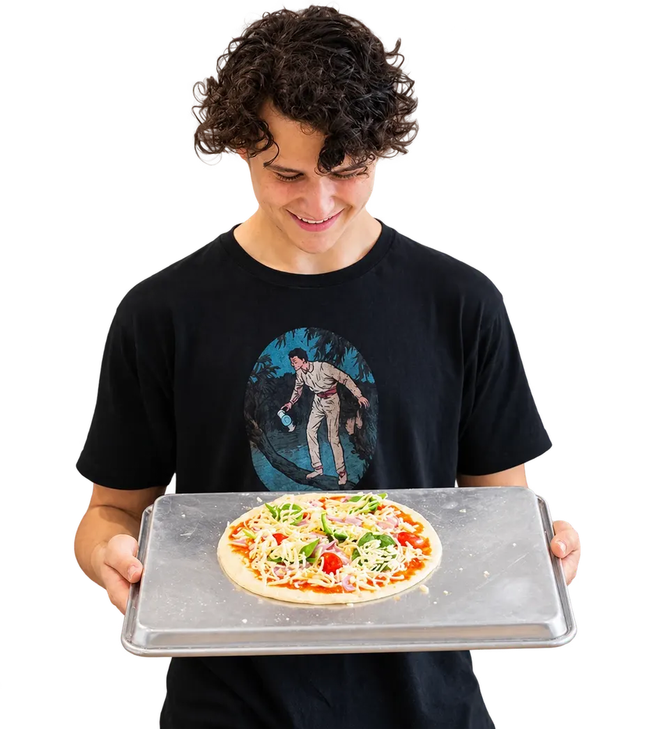 A smiling young man in a black t-shirt holding a tray with a freshly topped pizza