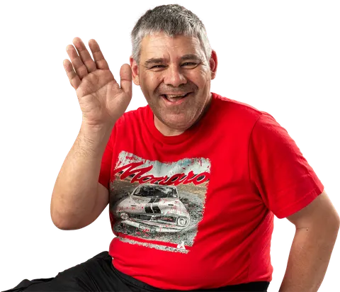 A smiling man in a red t-shirt waving hello