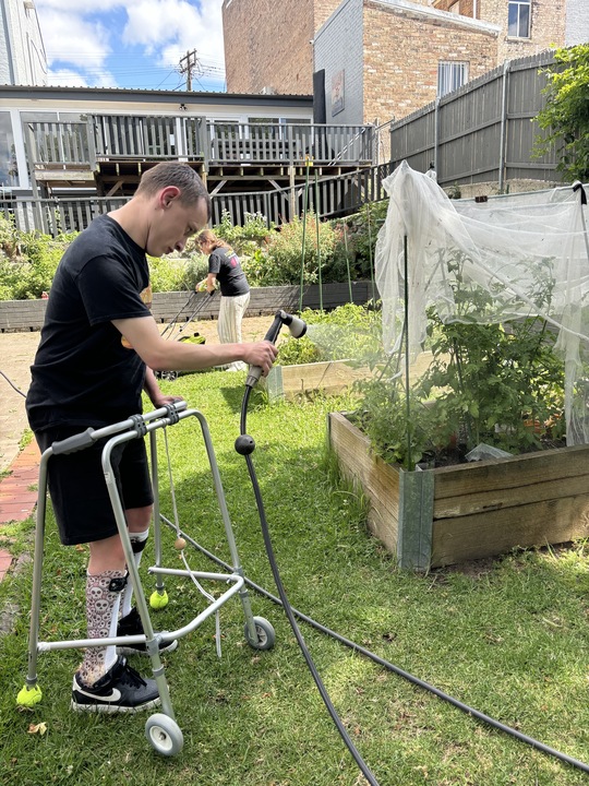 A person using a walking frame tends a raised garden bed