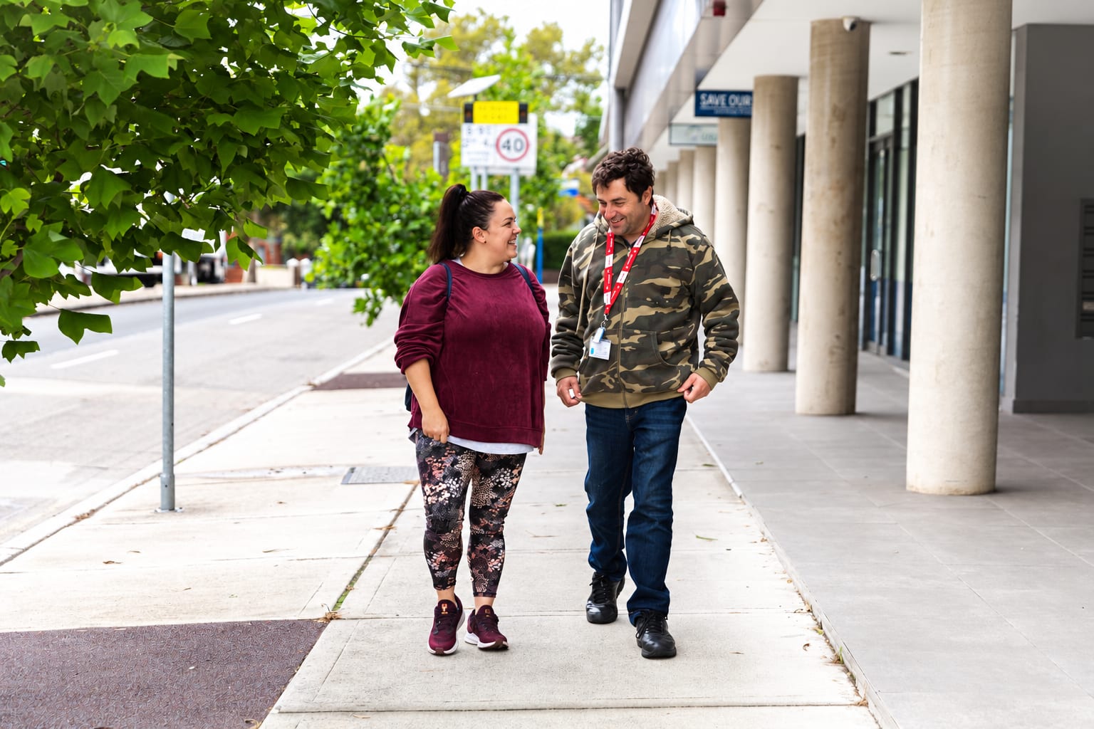 A together² support worker and a participant walking together along a suburban street, talking and laughing
